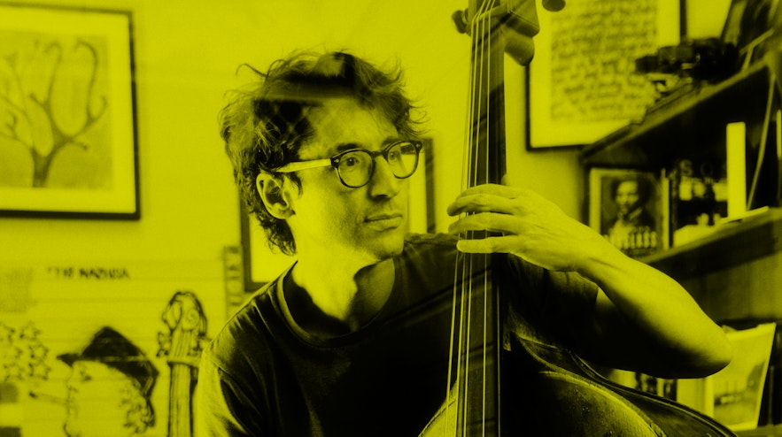 Person wearing glasses playing a double bass with a bow