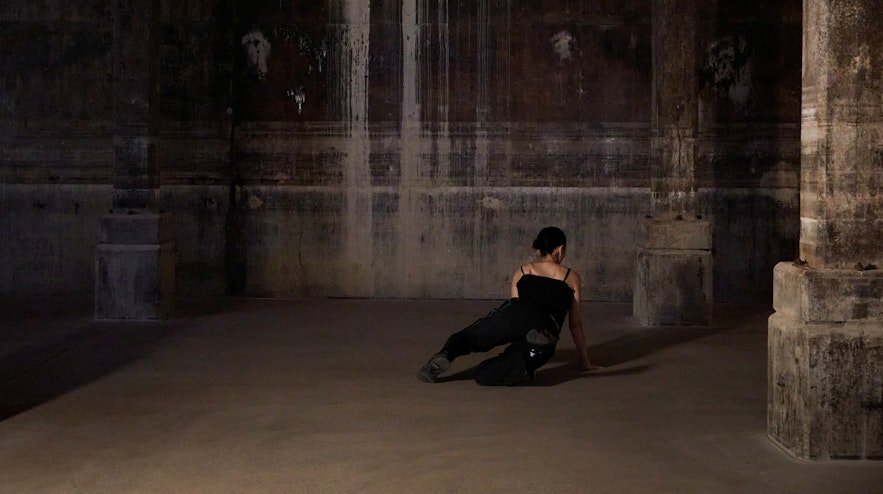 A person crawling on the concrete floor of a former World War 2 oil tank space
